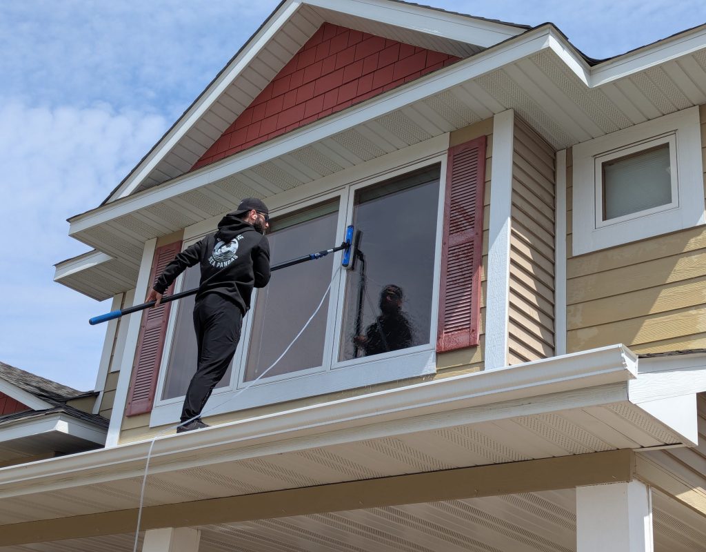 Technician using squeegee to clean large residential windows