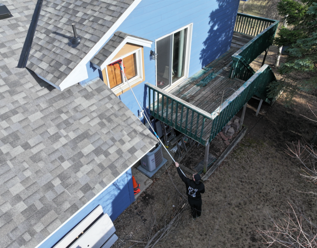 Orca Services and Window Washing technician cleaning gutters on a residential home in Farmington